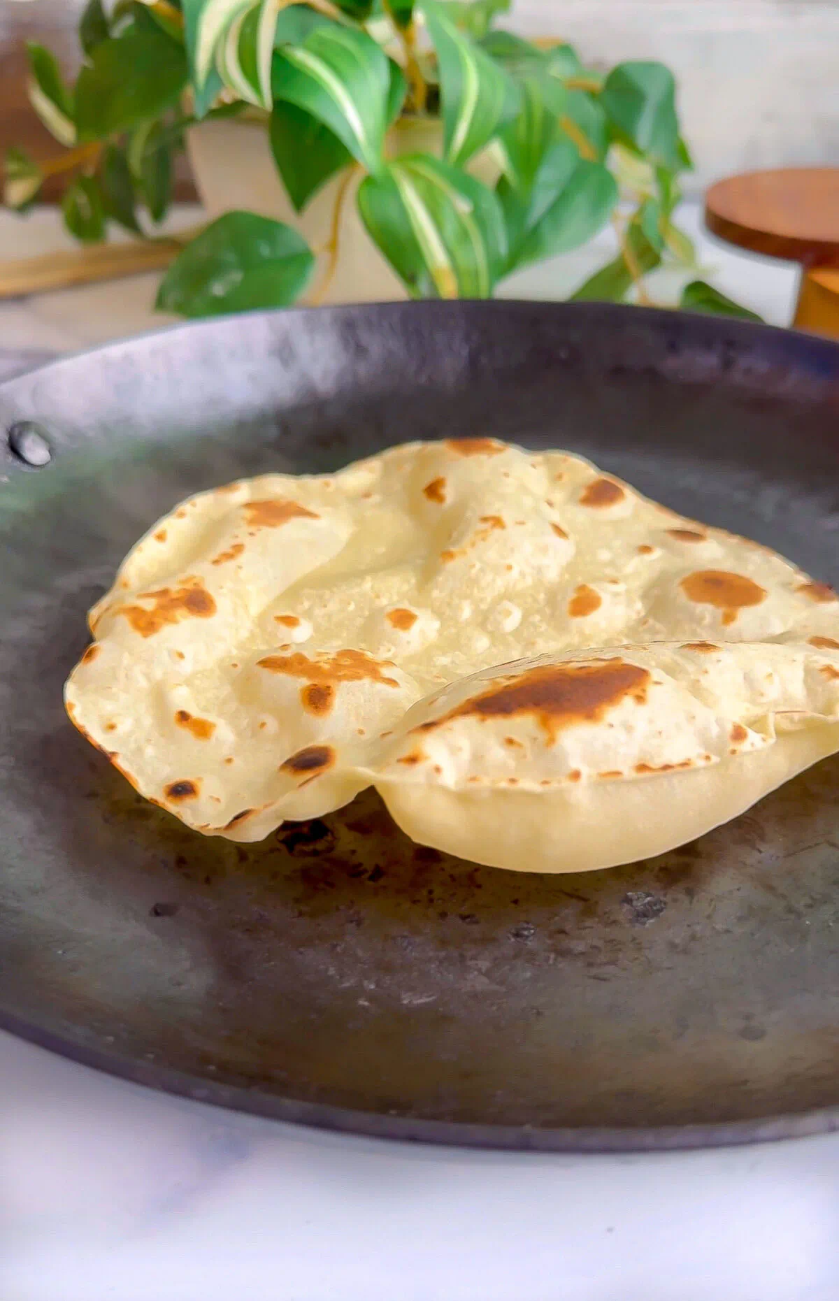 Sonoran flour tortilla puffed on a dark carbon steel comal