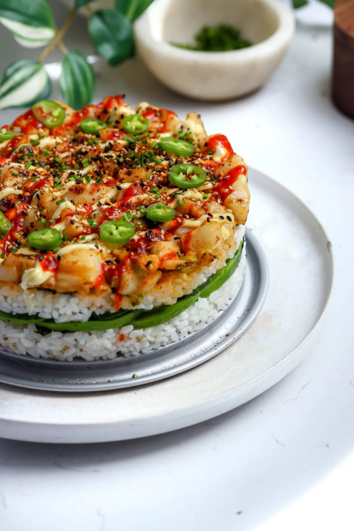 Baked sushi cake with spicy scallops broiled until caramelized, topped with Japanese mayo, sriracha, shichimi togarashi, and serrano slices.