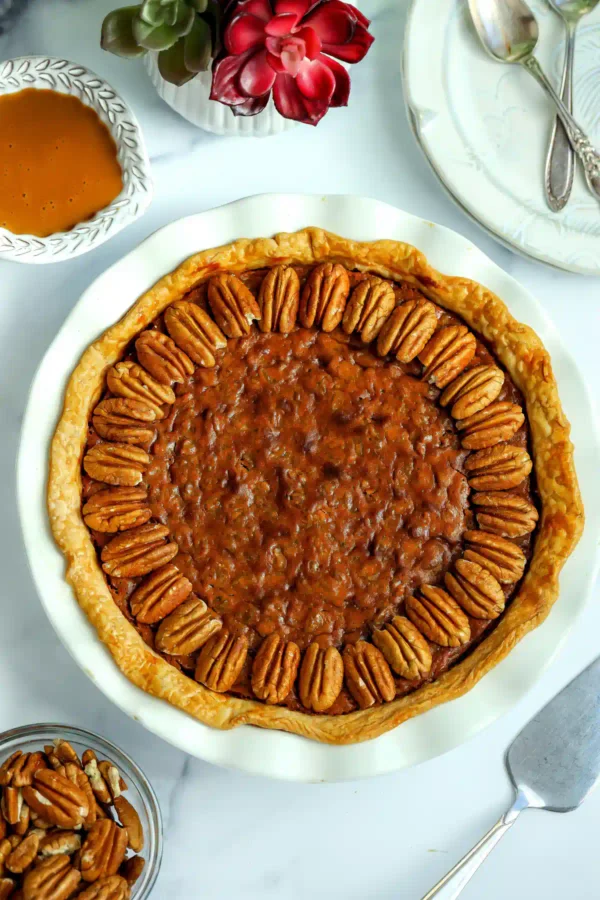 Overhead view of a whole dulce de leche pecan pie with a pecan border in a white pie dish. Title: Whole Dulce de Leche Pecan Pie
