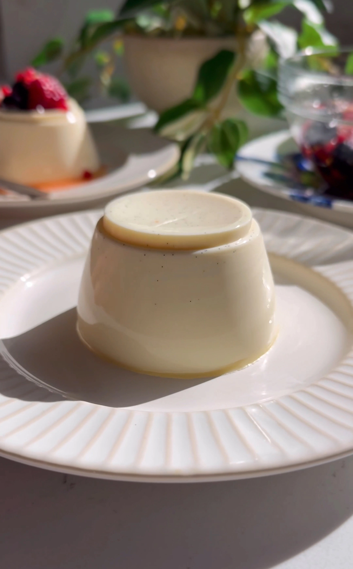Vanilla bean panna cotta unmolded onto a white plate, plain before adding berries