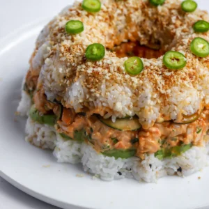 Shrimp sushi bundt cake topped with toasted panko, serrano slices, and unagi sauce.