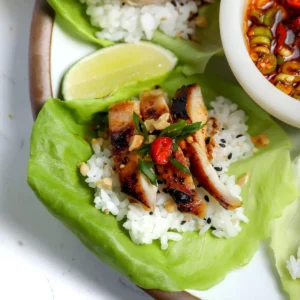 Miso chicken lettuce wraps on butter lettuce with rice, sliced chicken, scallions, fresno chile, and crushed cashews, served with a bowl of salsa macha and a lime wedge