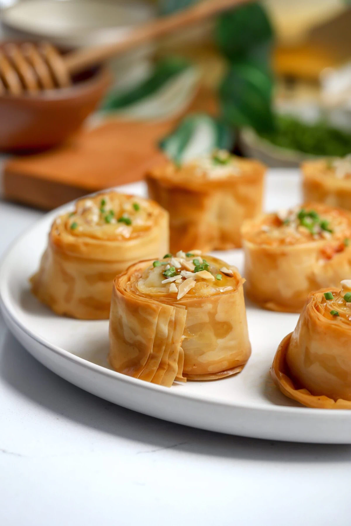 Bite-sized crispy baked phyllo with gruyere cheese between the layers. Topped with honey, chives, and toasted almonds.