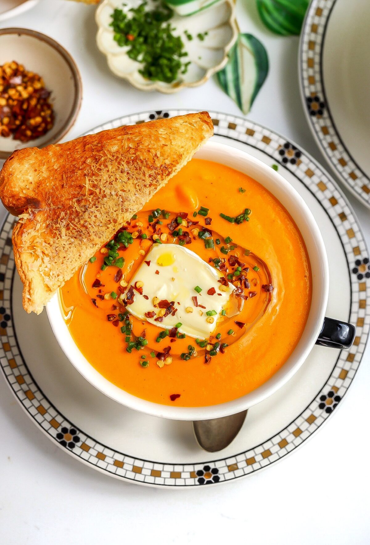 A bowl of honeynut squash soup with tomatoes and brie.