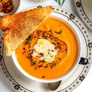 A bowl of honeynut squash soup with tomatoes and brie.