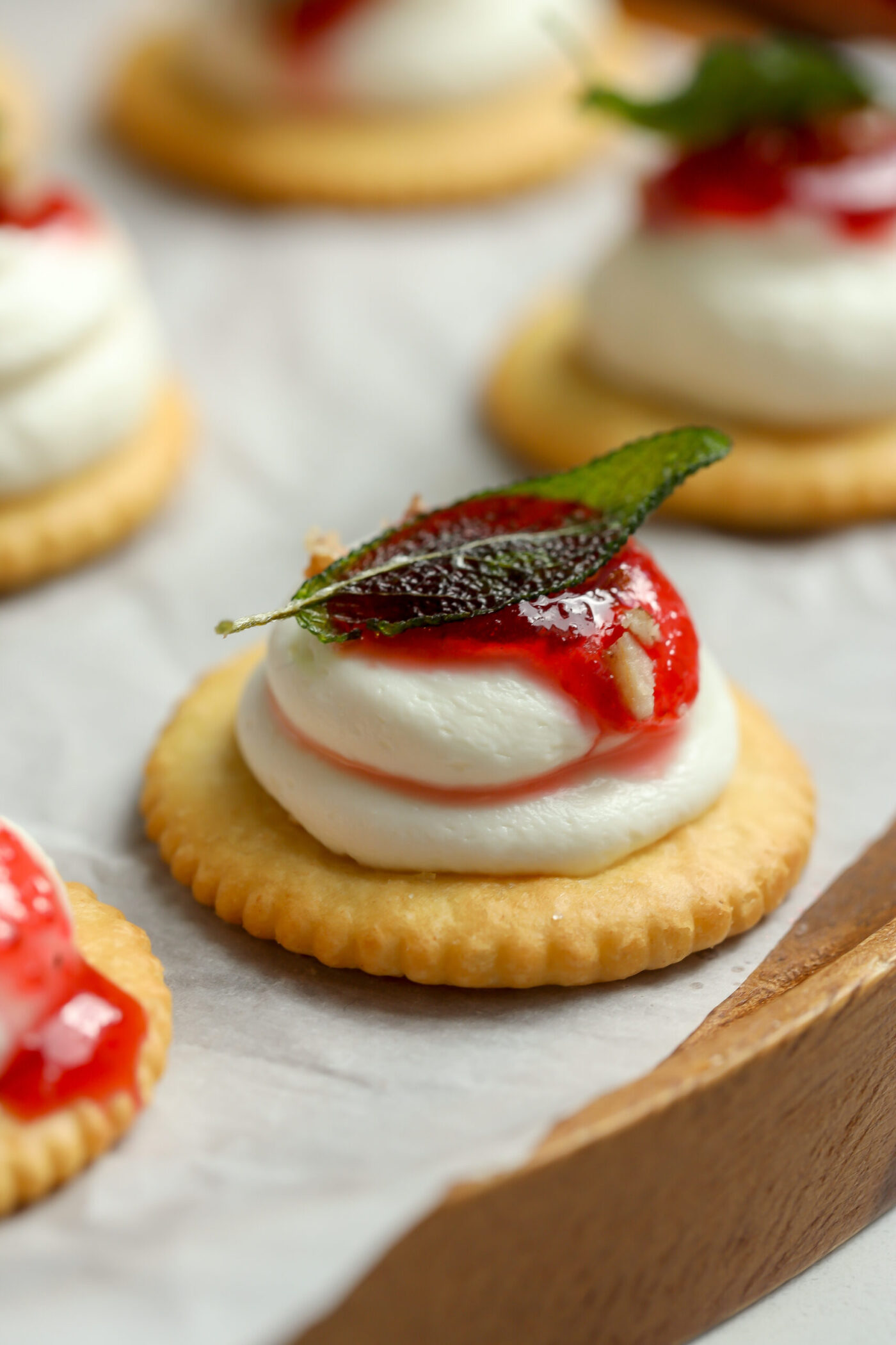 A Ritz cracker topped with a goat cheese and cream cheese blend. A spoonful of cranberry sauce placed on top of that finished off with a crispy fried sage leaf.