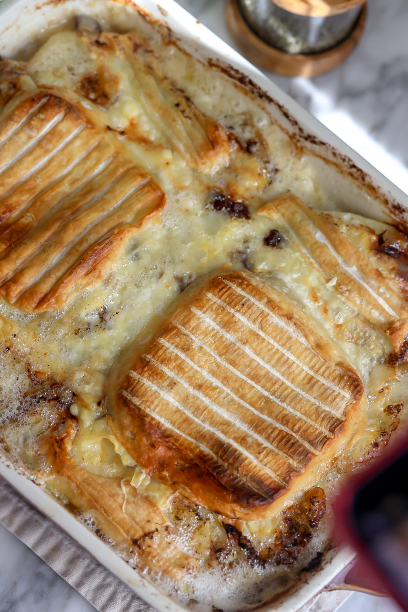 layers of peeled and sliced into a moon shaped potatoes topped with créme fraîche, black pepper, onions and crispy bacon and then repeated. On top is Riobiola cheese rind side down and baked to perfection.