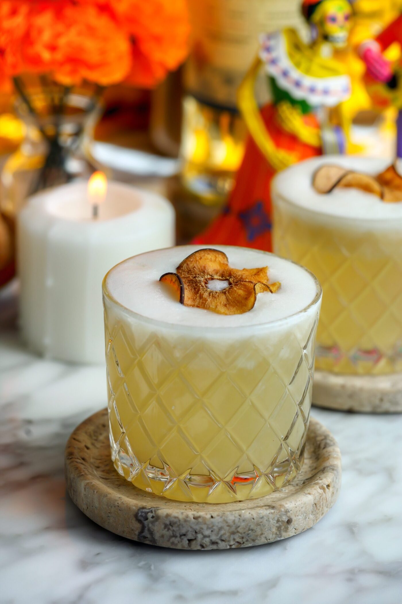A beautiful cocktail with a foam top, garnished with a dried pear.