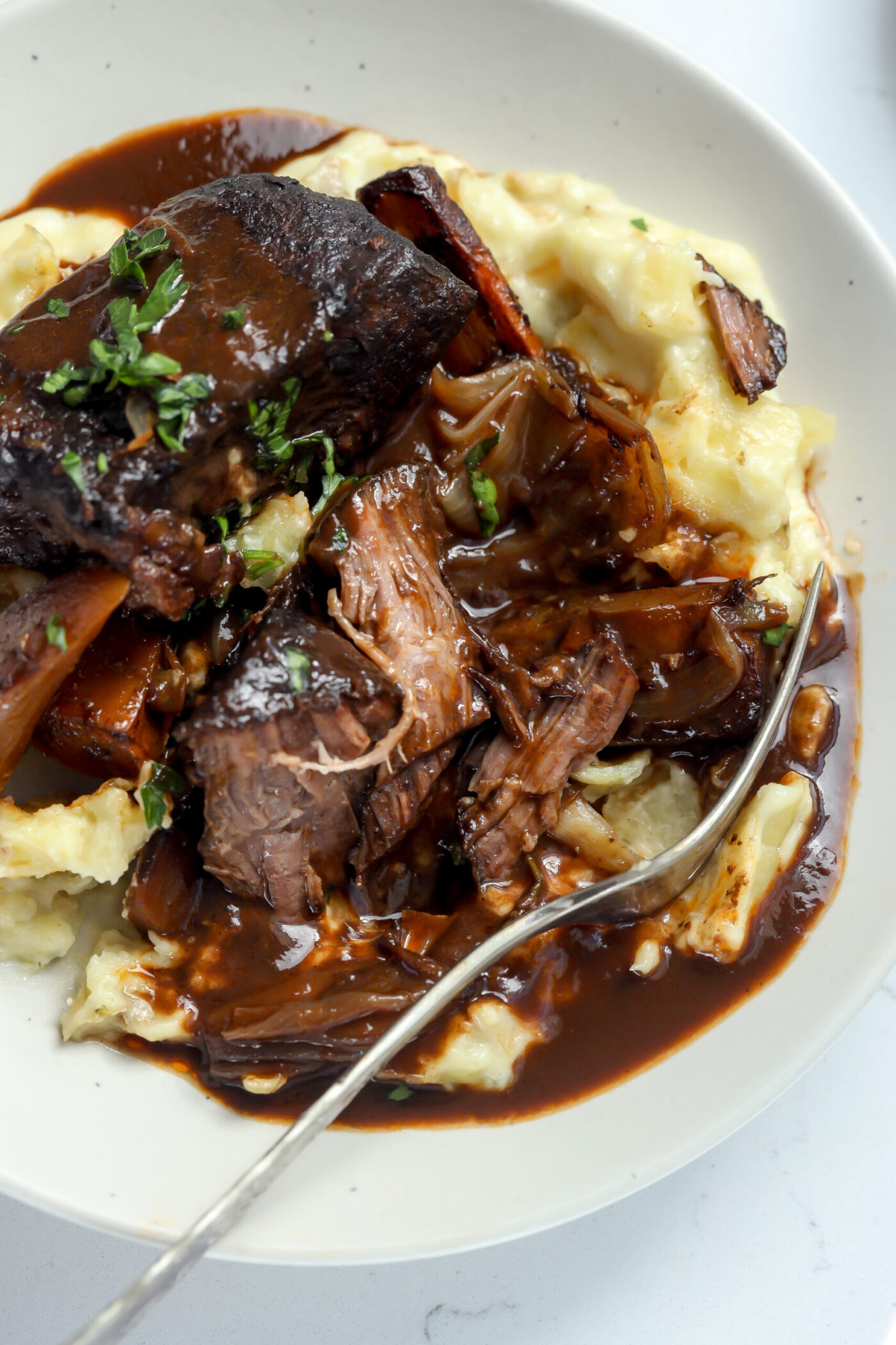 oven braised chuck roast with a gravy on top of a creamy mashed potato recipe