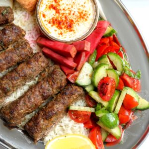 An easy to make Kabob Plate with ground beef and ground lamb skewers made in the oven, tomato salad, Syrian pickles with a tahini dipping sauce on the side.