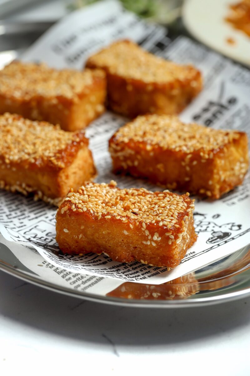 A toasted brioche bread with a honey brown sugar butter, dipped in sesame seeds to make a sesame seed candy.