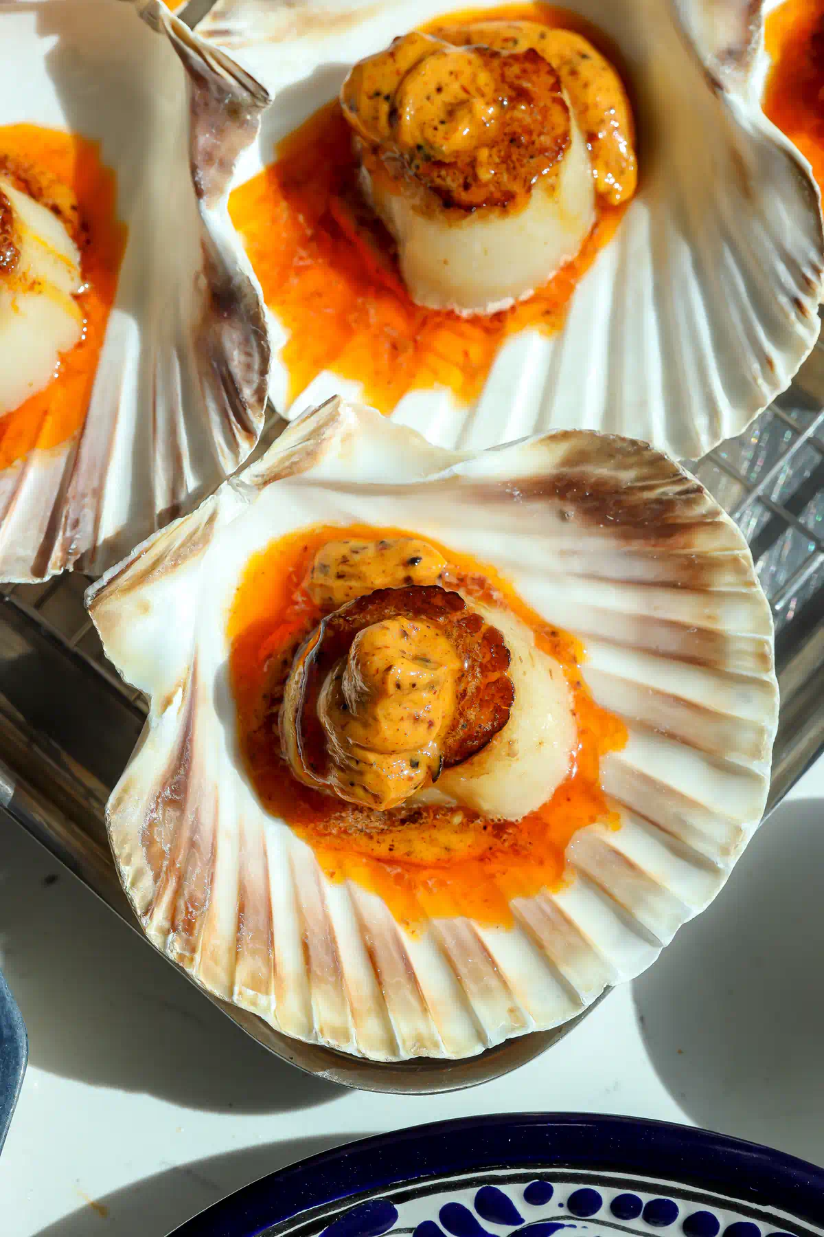 Two seared scallops in shells topped with salsa macha butter before going under the broiler