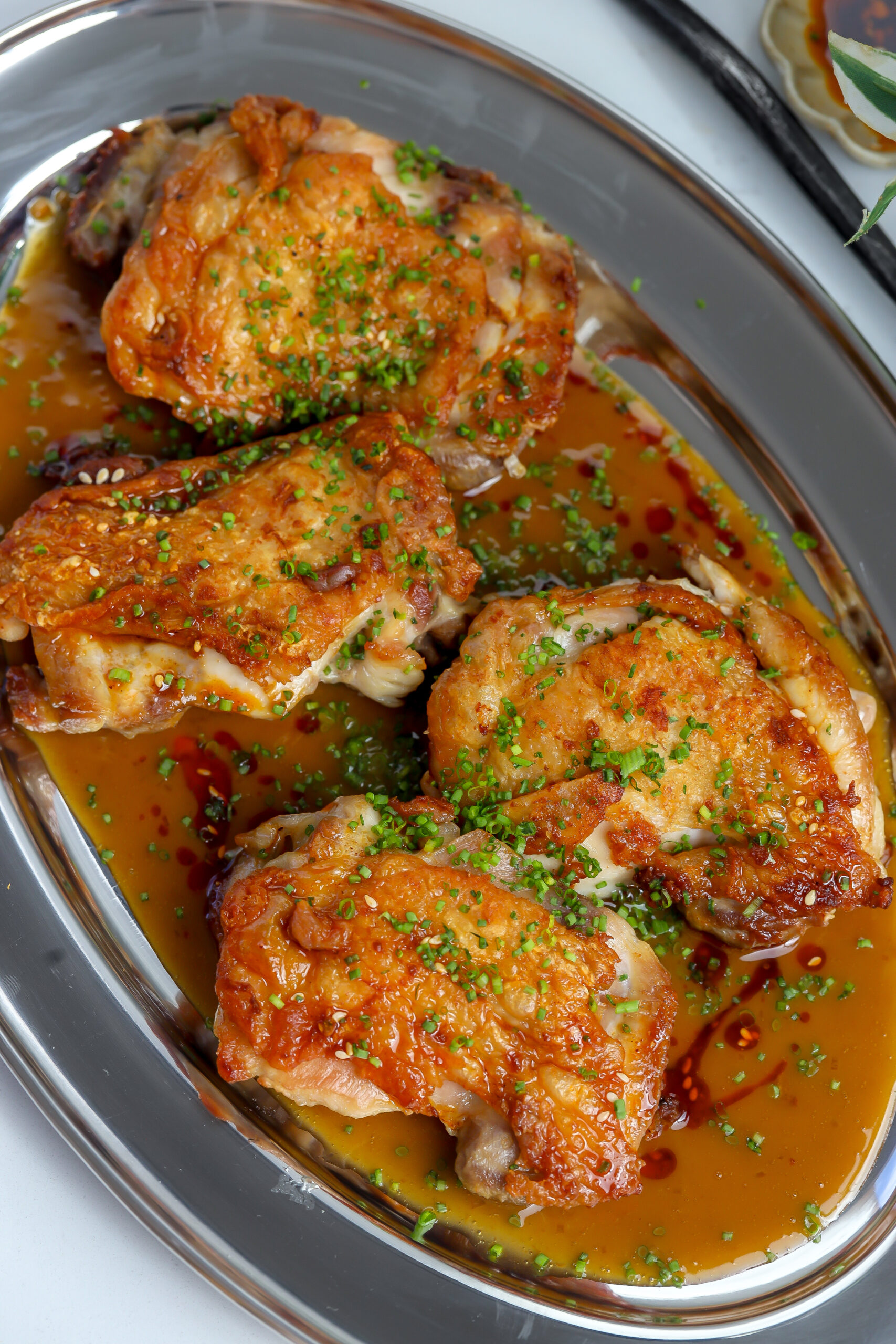Crispy chicken thighs seared in a skillet and covered in a sake butter sauce.