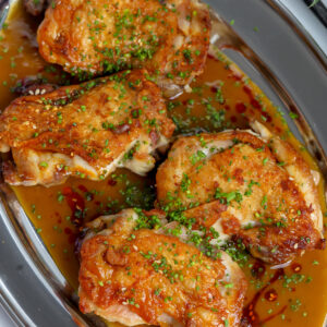 Crispy chicken thighs seared in a skillet and covered in a sake butter sauce.