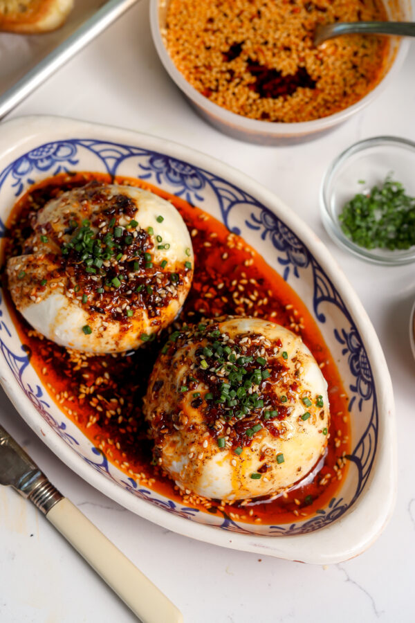 The perfect Italian and Japanese appetizer, two burrata cheese balls sitting on a platter covered in a Calabrian chili crisp oil and chives.