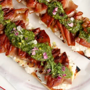 Mortadella Tartine with a homemade Stracciatella & Pistachio sauce on a plate.