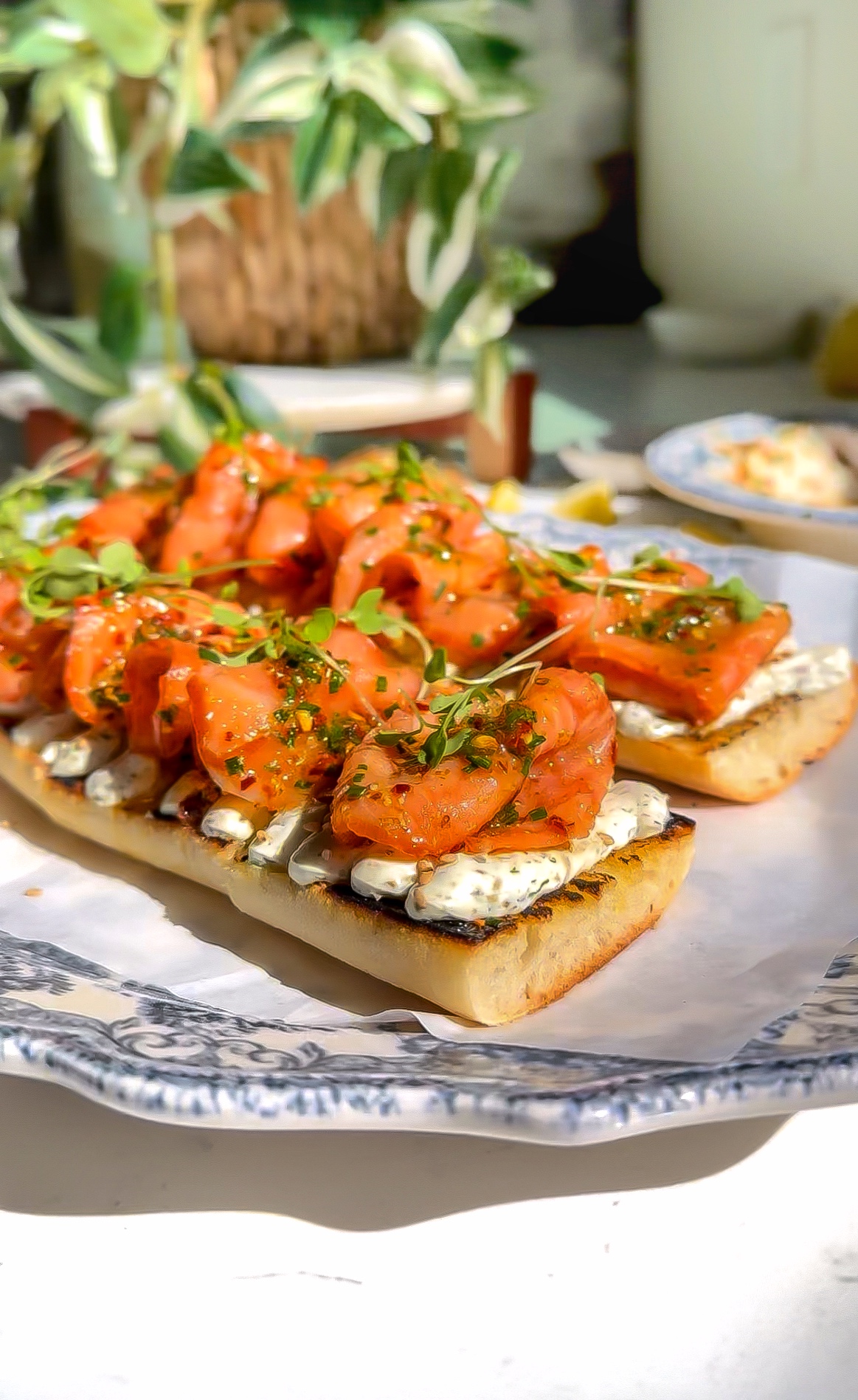 smoked salmon that has been marinated on top of a delicious whipped cheese mixture and then place on a baguette to make a Tartine sitting on a plate.