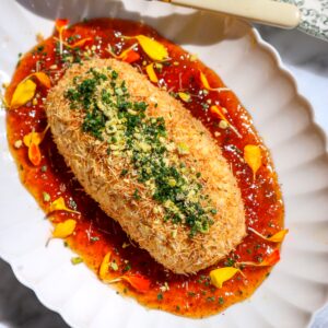 A recipe for whipped feta and cream cheese with a chipotle fig jam inside, coated in toasted kataifi on a plate.