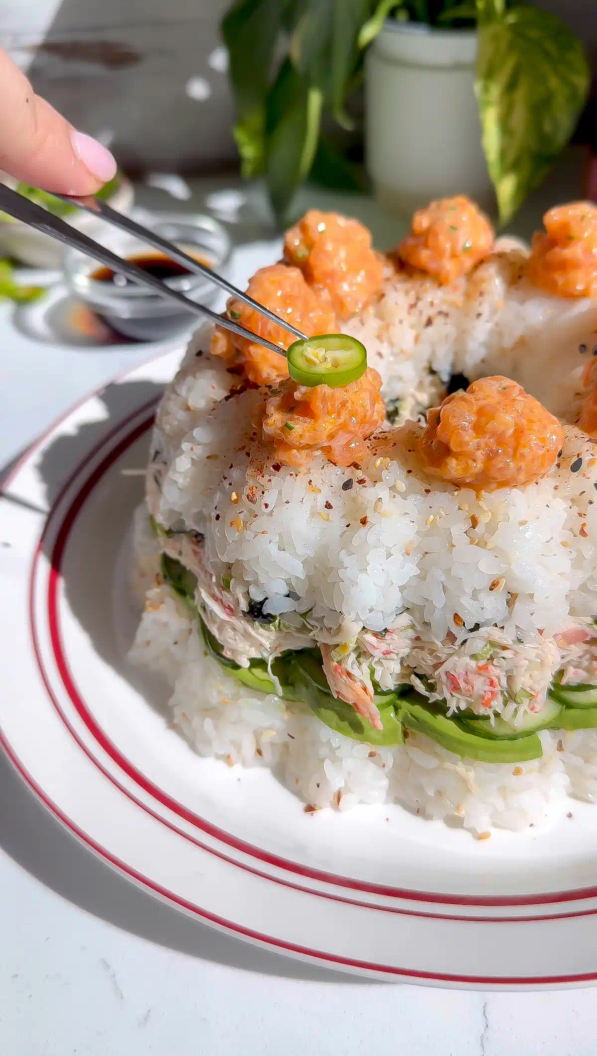 Crab tampico sushi bundt cake topped with piped spicy salmon dollops, sliced serranos, and shichimi togarashi.