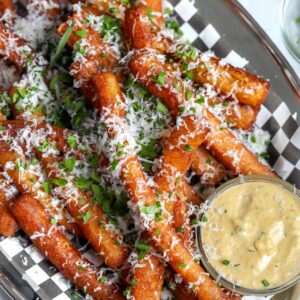 Japanese long French fries perfectly seasoned and topped with cheese and chives with a caramelized shallot mayo in a ramekin on the side.