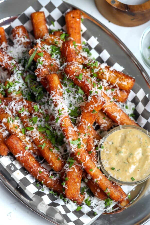 Japanese long French fries perfectly seasoned and topped with cheese and chives with a caramelized shallot mayo in a ramekin on the side.