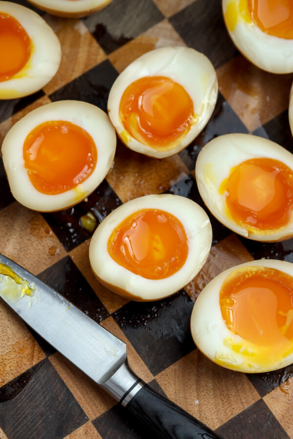 A recipe for perfectly cooked soft-boiled jammy eggs cut in half and ready to be placed in a ramen soup.