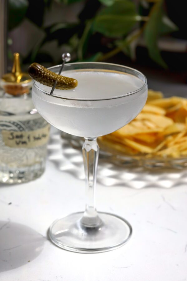 A coupe glass with a vodka dirty Salty Vinegartini inside that is an easy recipe to make.