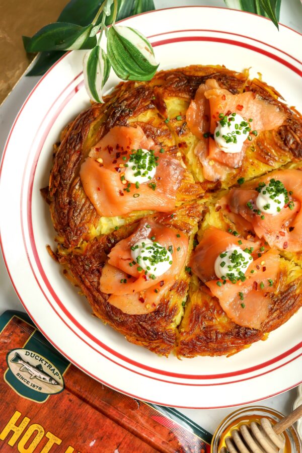 A appetizer recipe for a rosti with smoked salmon, creme friache and chives on top.