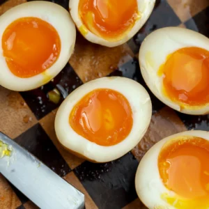 A recipe for perfectly cooked jammy eggs cut in half and ready to be placed in a ramen soup.