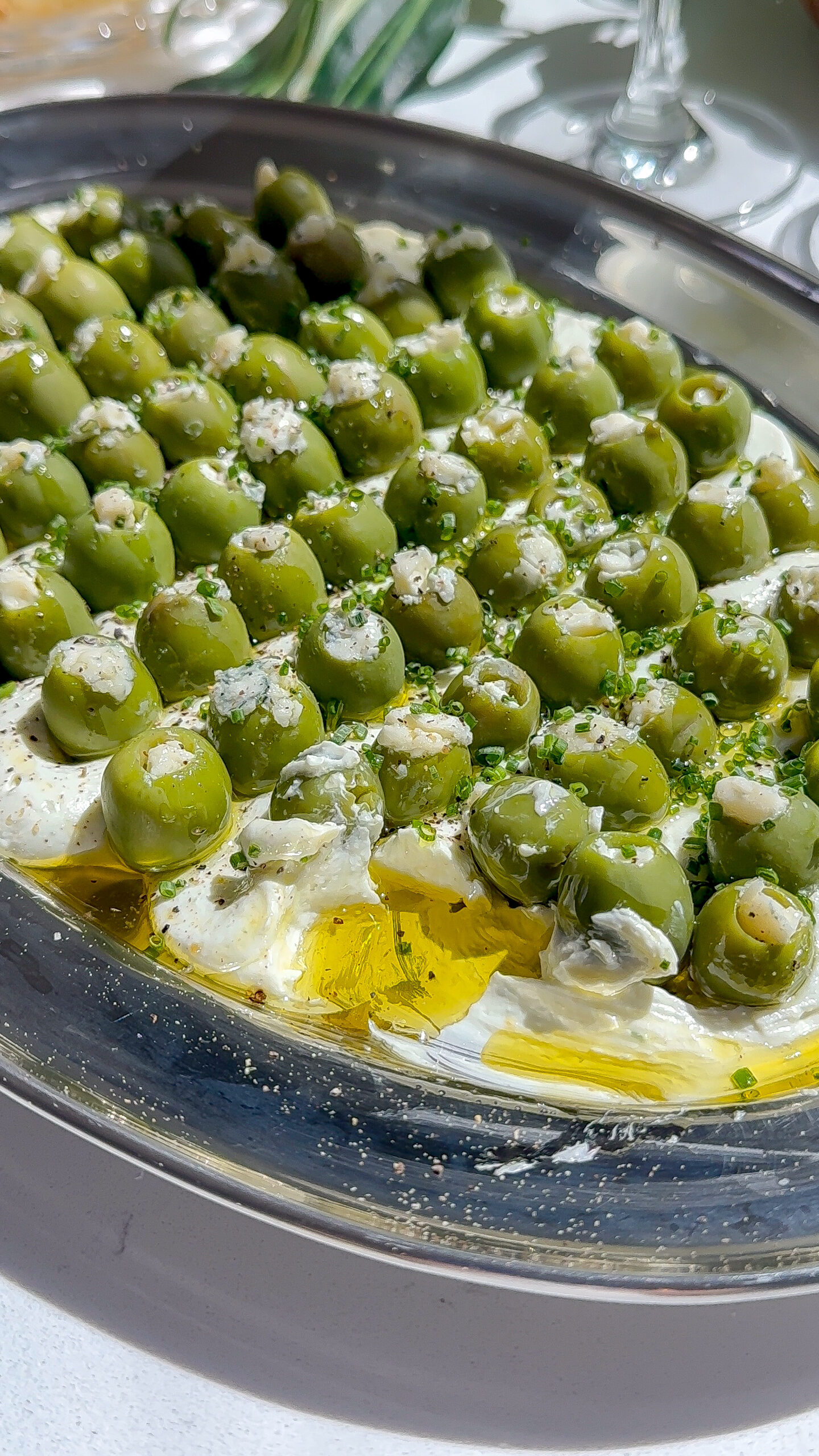 This is a blue cheese and cream cheese dip with a bunch of other savory seasonings spread on a plate and topped with blue cheese stuffed olives, the perfect dirty martini easy make-ahead appetizer.