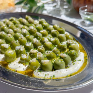 This is a blue cheese and cream cheese dip with a bunch of other savory seasonings spread on a plate and topped with blue cheese stuffed olives, the perfect dirty martini recipe.