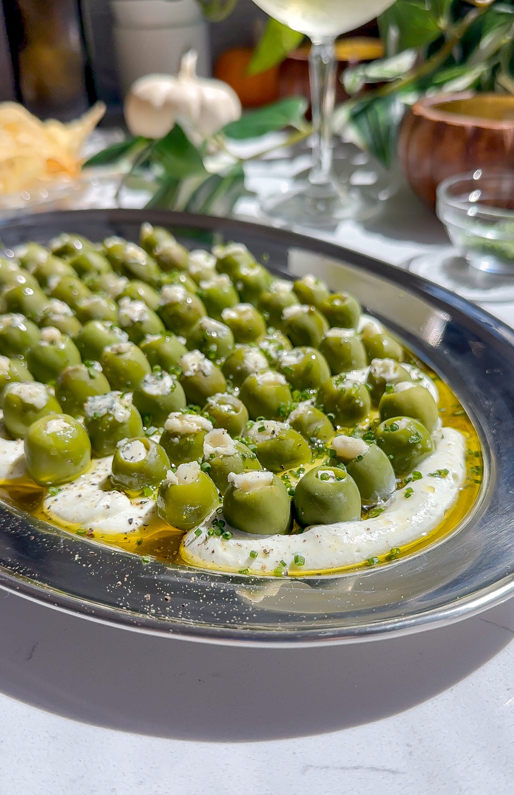 This is a blue cheese and cream cheese dip with a bunch of other savory seasonings spread on a plate and topped with blue cheese stuffed olives, the perfect dirty martini recipe.