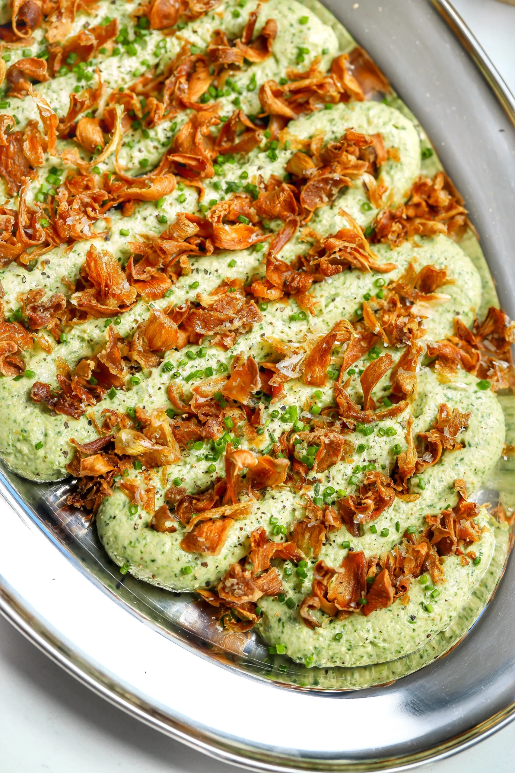 A cold, creamy spinach and artichoke dip recipe with crispy artichokes on top.