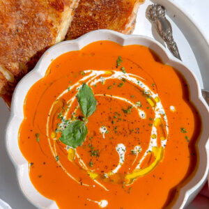 a luxurious fall tomato bisque basil soup recipe with grilled cheese on the side.