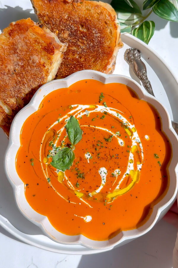 a luxurious fall tomato bisque basil soup recipe with grilled cheese on the side.