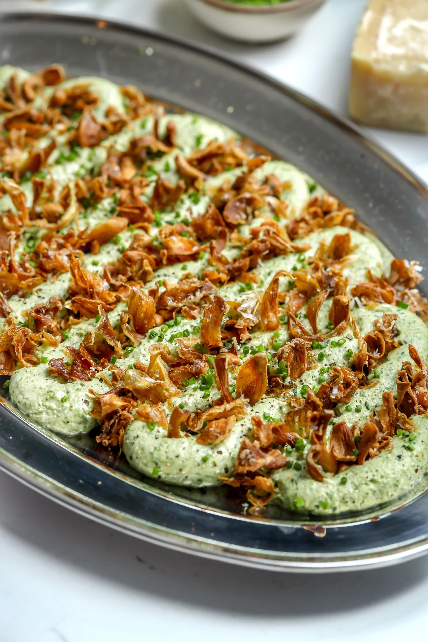 A cold, creamy spinach and artichoke dip recipe with crispy artichokes on top.