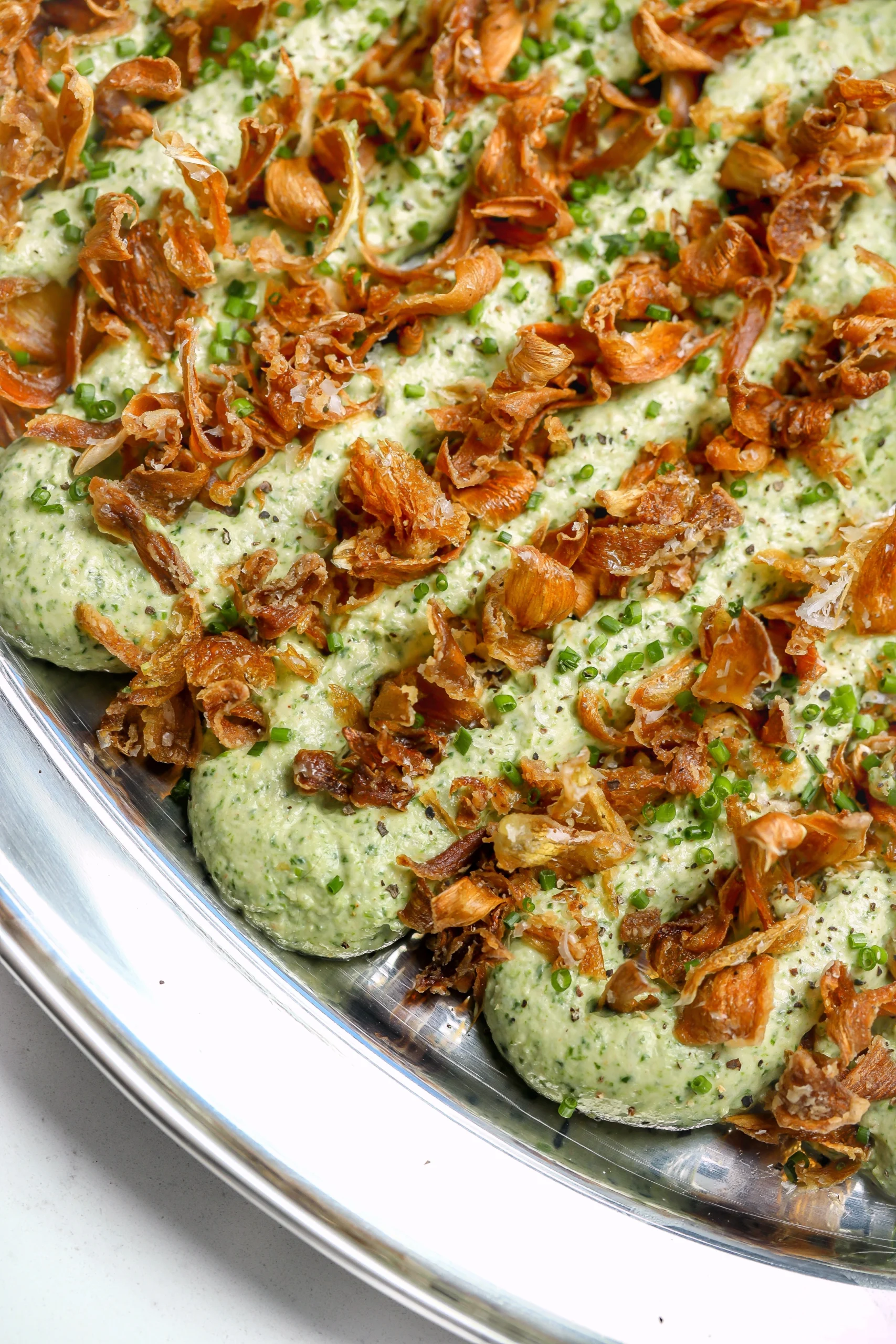 A cold, creamy spinach and artichoke dip recipe with crispy artichokes on top.