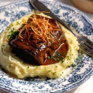 Boneless braised beef recipe with mashed potatoes on a blue floral plate