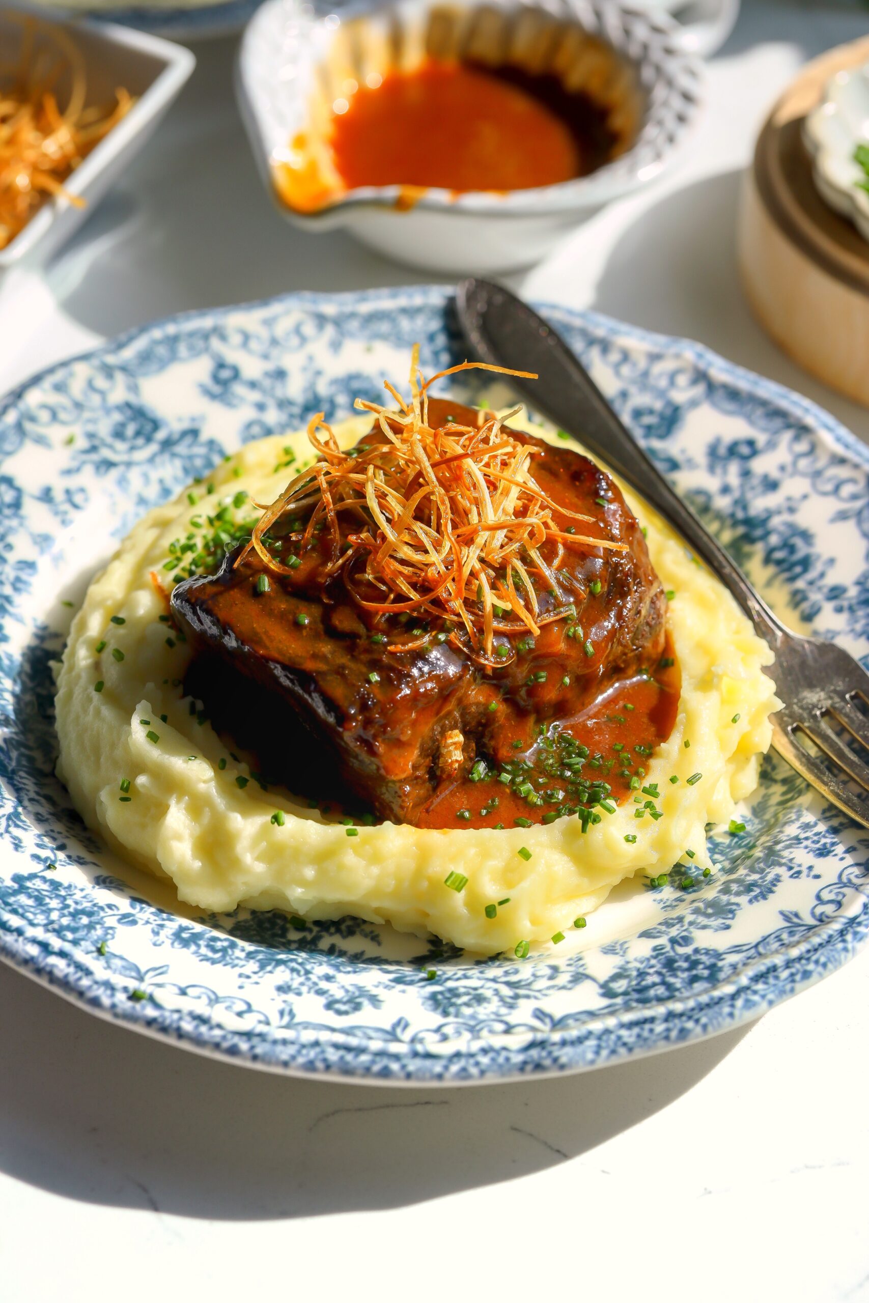 Braised beef plated with mashed potatoes in natural light.