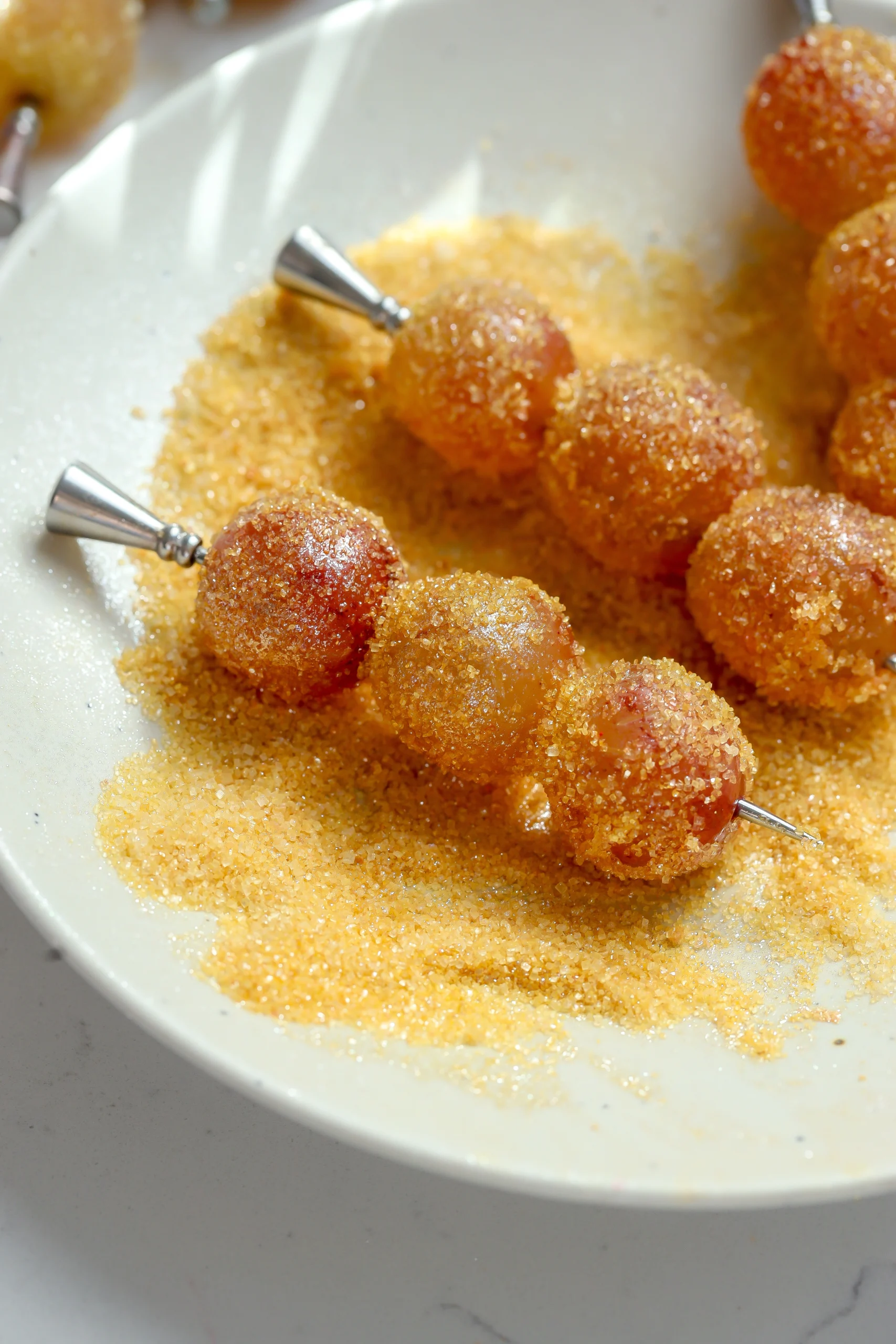 Lemon sugar coated boozy grapes skewered on cocktail picks with a sparkling finish.