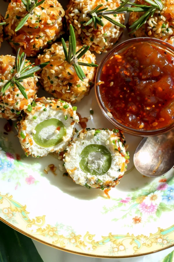 Boursin cheese stuffed olives coated in sesame and crispy shallots with a sliced olive showing the creamy cheese center