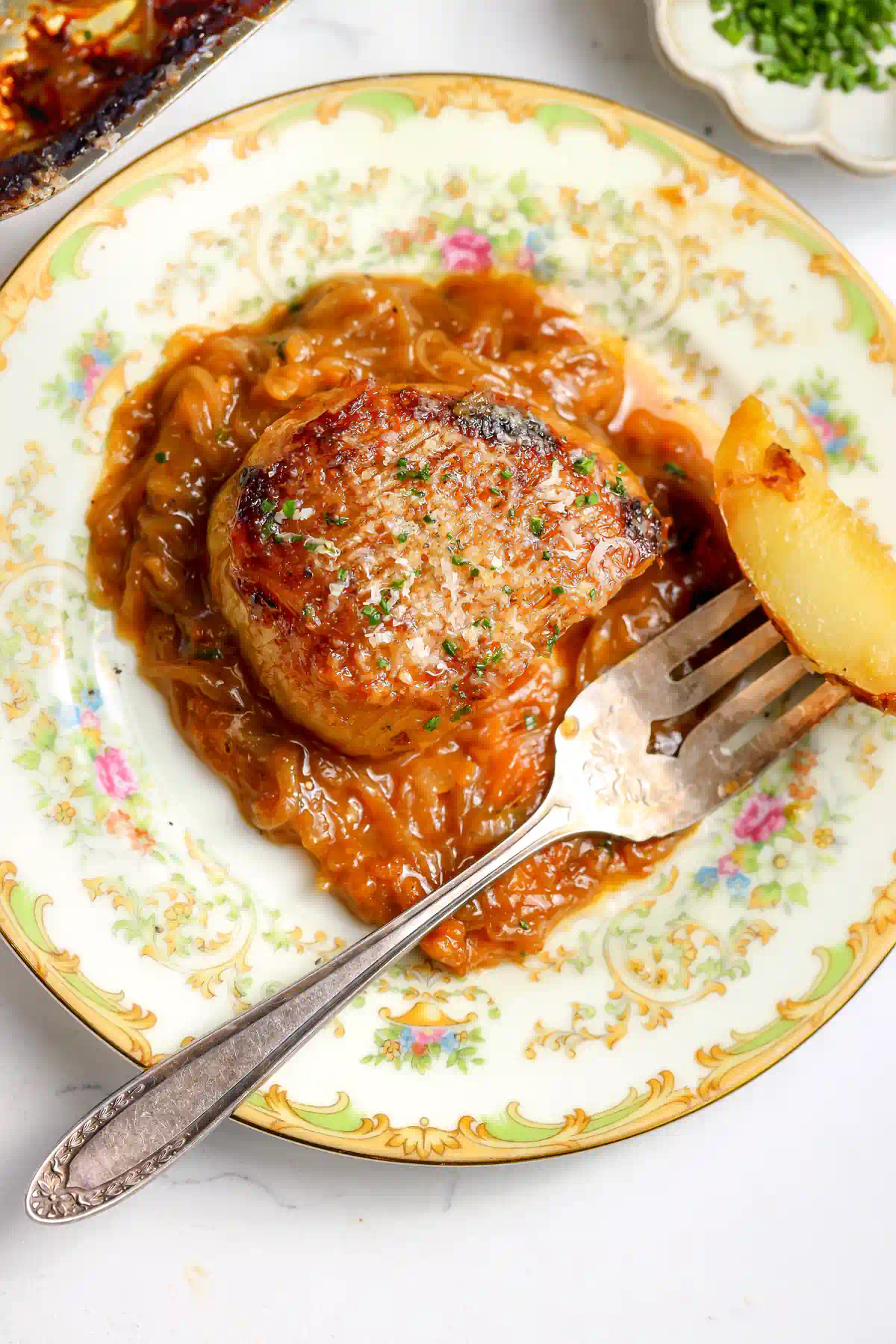Plated french onion hasselback potatoes served over caramelized onion gravy