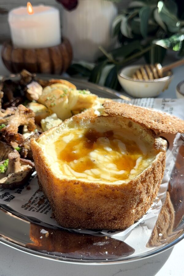 Fried brie appetizer topped with roasted truffle mushrooms and honey on warm baguette