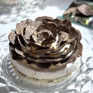Truffle brie cake with whipped brie layers topped with shaved truffle flower on a glass plate