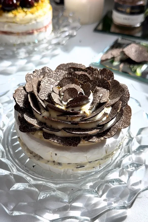 Truffle brie cake with whipped brie layers topped with shaved truffle flower on a glass plate