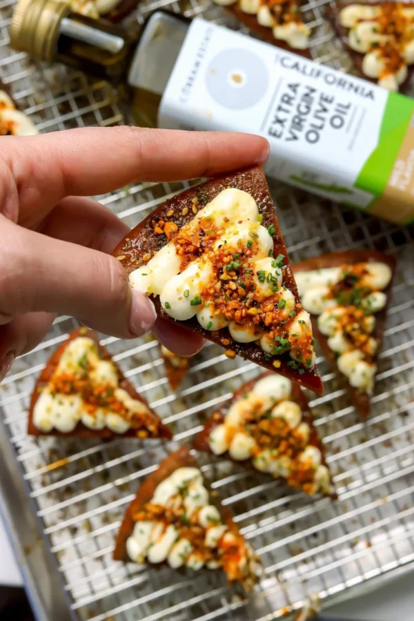 Whipped feta crostini made with fried pita, piped whipped feta, and pistachio salsa macha