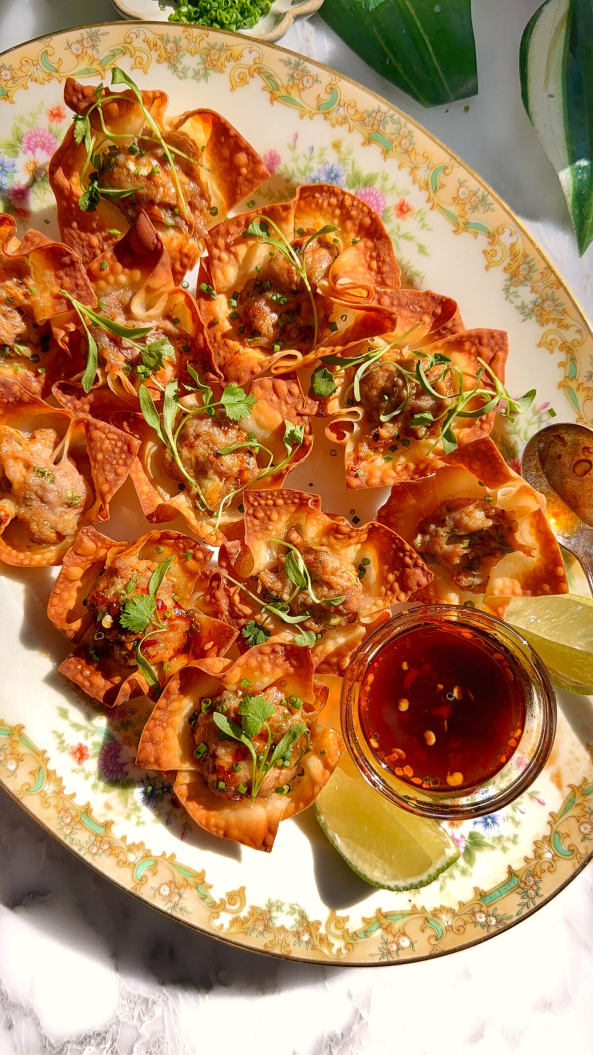Baked pork and shrimp wonton cups arranged on a platter with dipping sauce and herbs