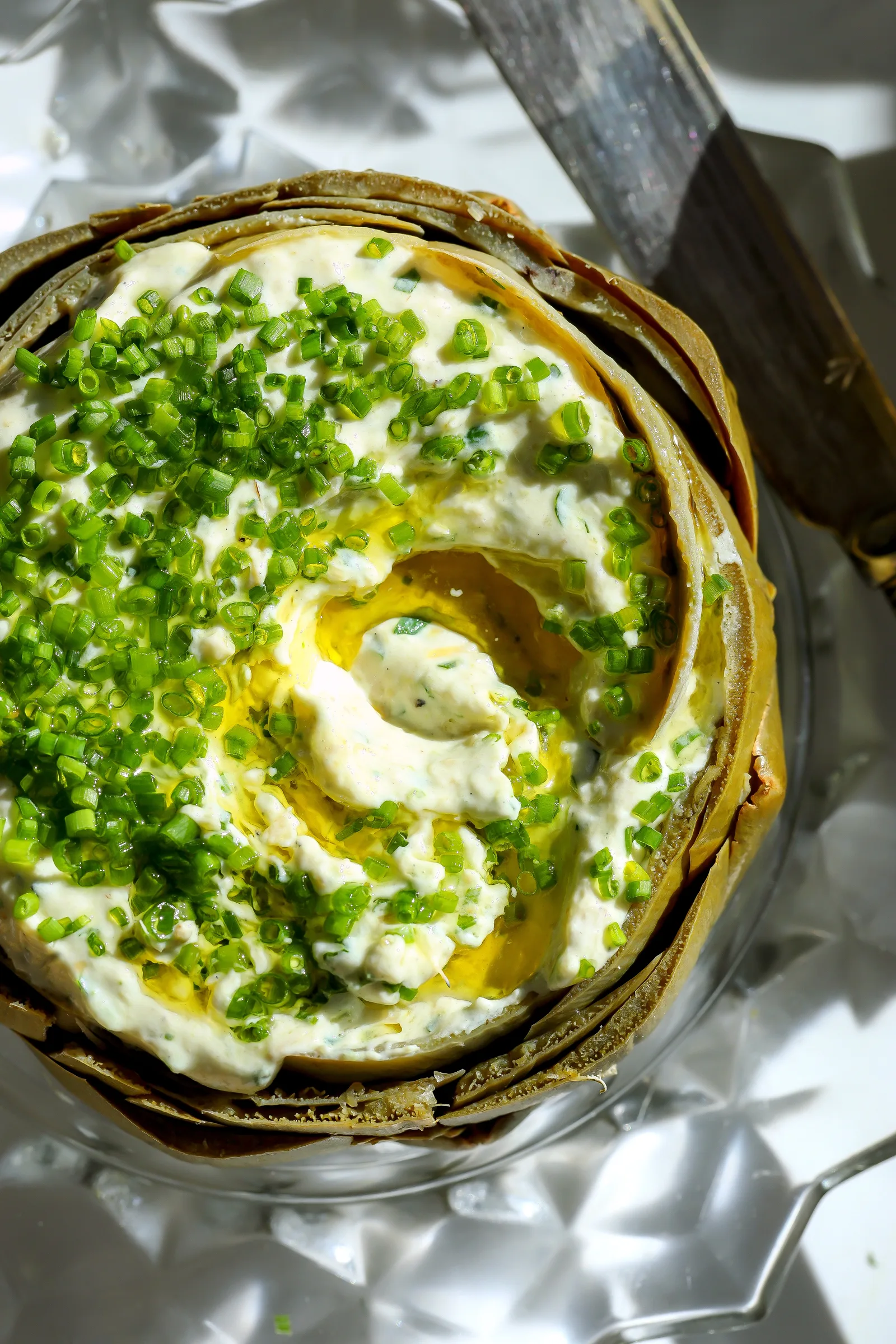 Overhead view of cold artichoke dip with a scoop taken out to show the creamy texture