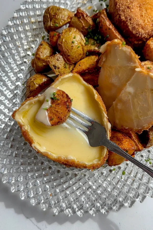 A fried cheese heart with the top rind removed, revealing a gooey, melted interior ready for dipping.
