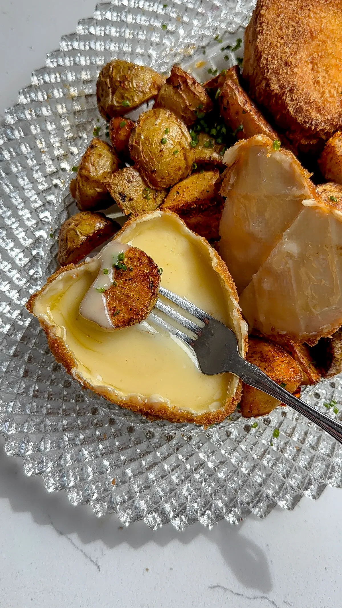 A fried cheese heart with the top rind removed, revealing a gooey, melted interior ready for dipping.
